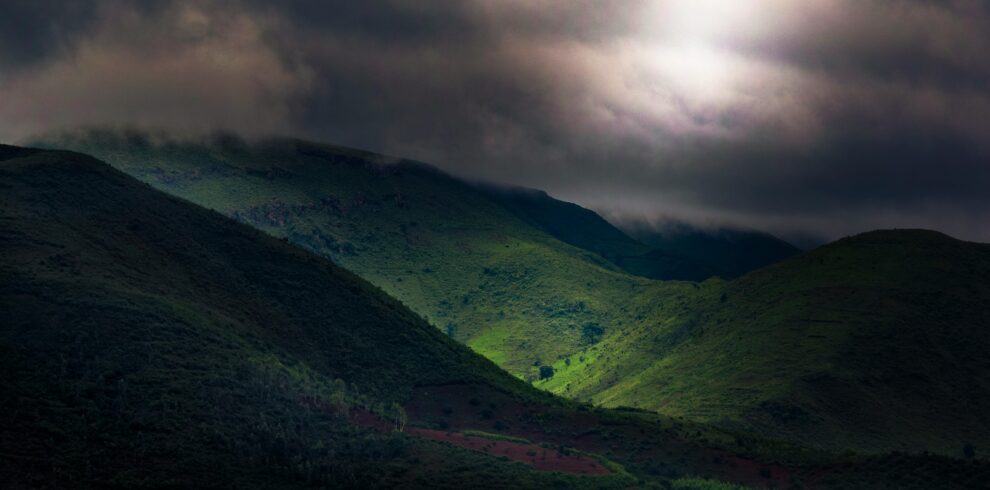 Scenic view of Koraput hills under dramatic clouds, displaying lush greenery and dynamic lighting.
