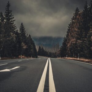 A moody highway through the forest in Harz, Germany, under dark clouds.