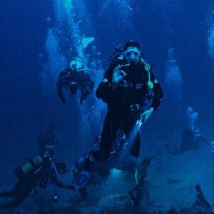 A group of scuba divers exploring a submerged shipwreck in the ocean.