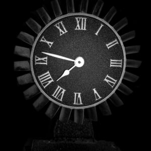 Stylish black clock with Roman numerals against a dark background.