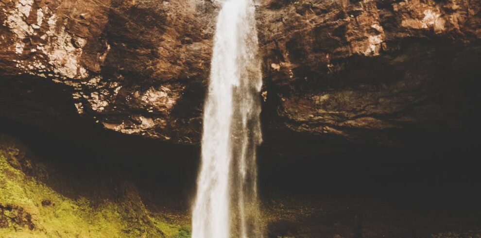 Stunning waterfall cascading down a rocky cliff surrounded by lush greenery in Patnus, India.