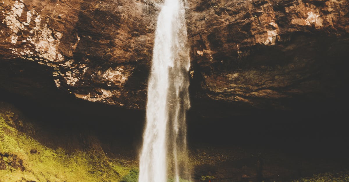 Stunning waterfall cascading down a rocky cliff surrounded by lush greenery in Patnus, India.